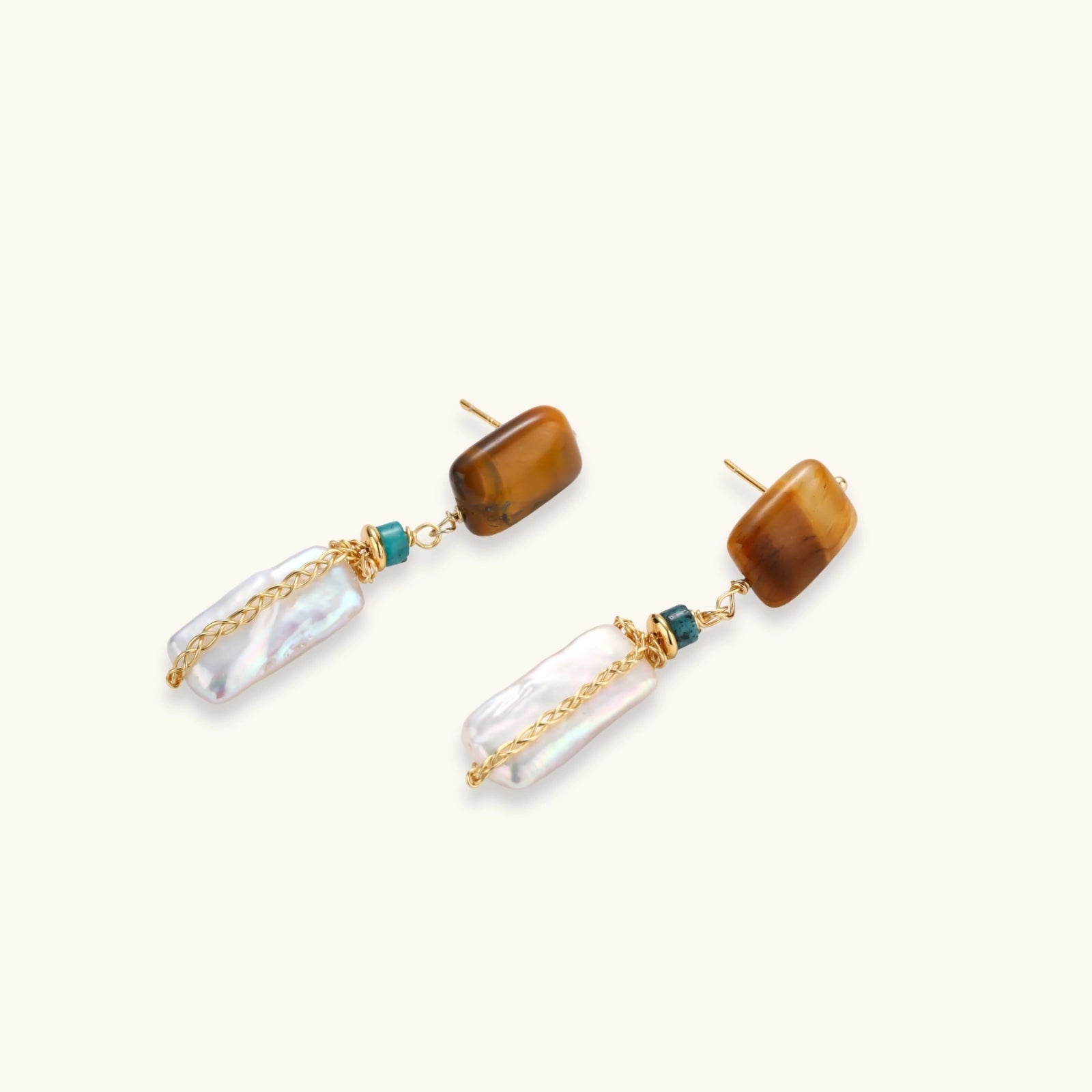 Gold-plated drop earrings with amber stones, teal beads, and wire-wrapped baroque pearls on cream background.
